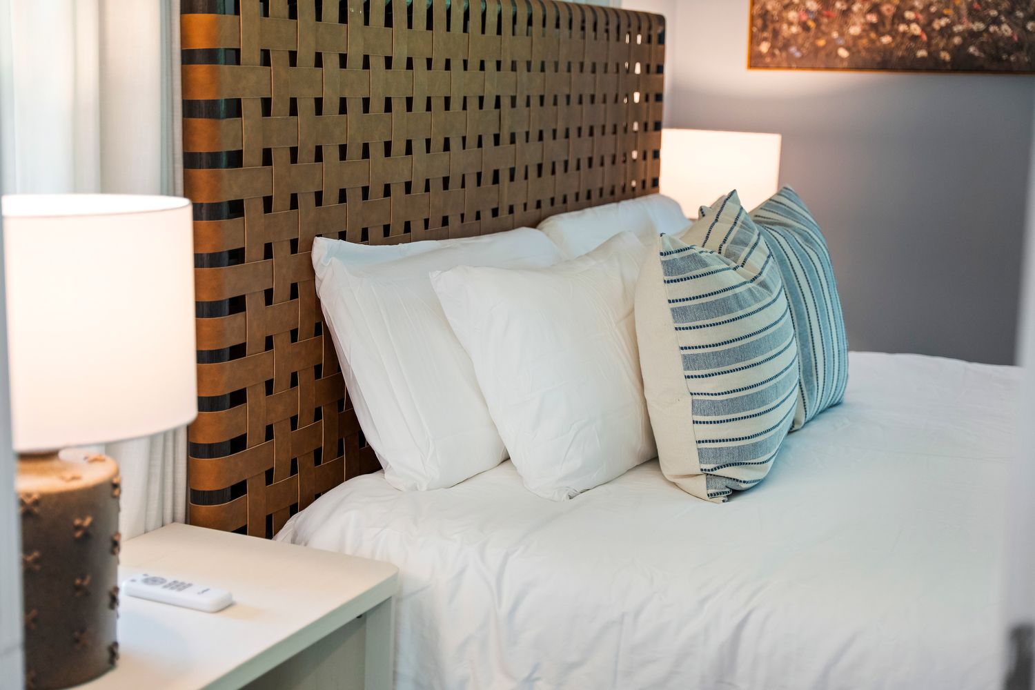 Crisp white bedding against a woven leather headboard.