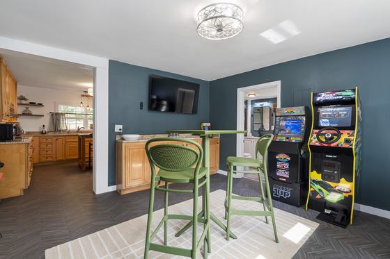 Game room looking through to the kitchen, arcade cabinets along the wall.