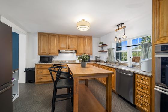 Kitchen with honey oak cabinets, a butcher block island, stainless appliances and pendant lights.