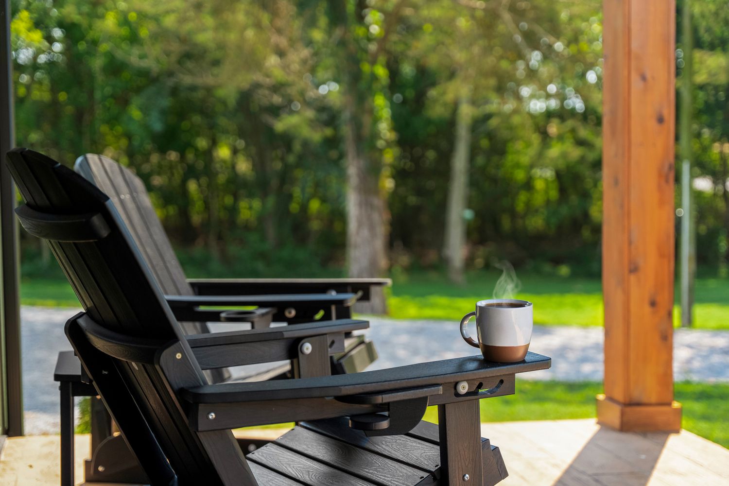 A mug of coffee on the arm of a porch chair in morning light.