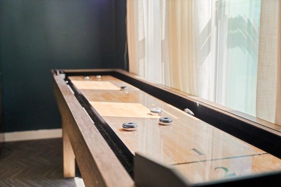 Close view along the polished shuffleboard table with pucks set out.